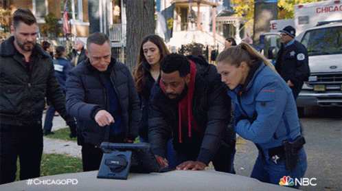 Group Of Police Officers Looking At Tablet On Car Hood GIF