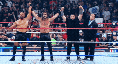 Group Of Wrestlers With Hands In The Air In Ring GIF