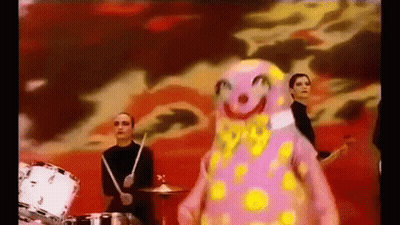 Group Playing Drums In Front Of Pink Clown GIF