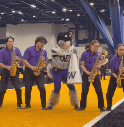 Group Playing Saxophones With Husky Mascot Holding Bag Saying W GIF