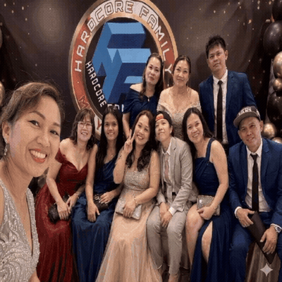 Group Posing In Front Of Hardcore Family Banner GIF