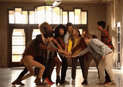 Group Putting Hands Together In Circle In Front Of Exit Sign GIF