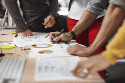 Group Sitting Around Table Looking At Graphs GIF