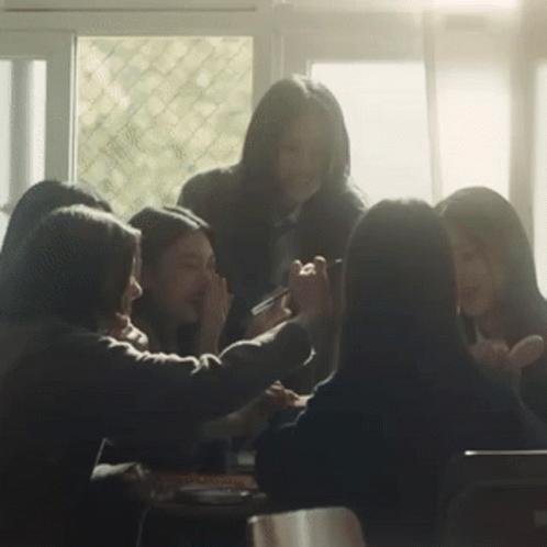Group Sitting Around Table With Hands On Faces GIF