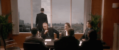 Group Sitting Around Table With Man Standing In Window GIF