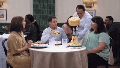Group Sitting At Table While Man Holds Cake GIF