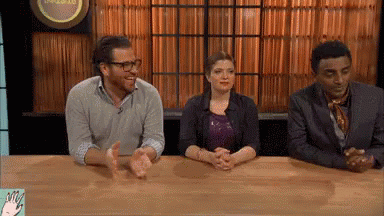 Group Sitting At Table With Hands Folded In Front Of Sign A GIF