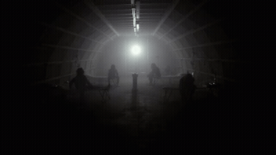 Group Sitting In Dark Room With Light Through Ceiling GIF