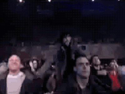 Group Sitting In Dark Room With Man Standing In Middle GIF