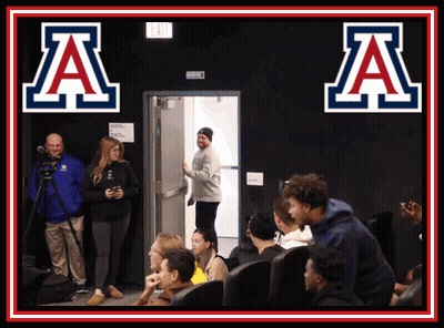 Group Sitting In Front Of Sign Saying A GIF