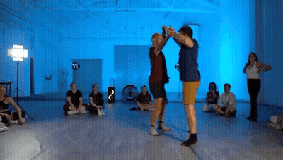 Group Sitting On Floor With Blue Lights While Man And Woman Dancing GIF