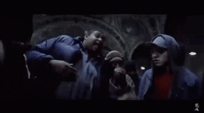 Group Standing Around Man In Dark Room GIF