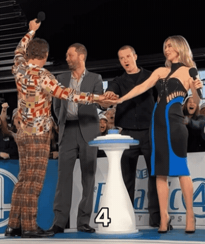 Group Standing Around Table With Number 4 GIF