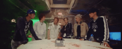 Group Standing Around Table With Red Exit Button GIF
