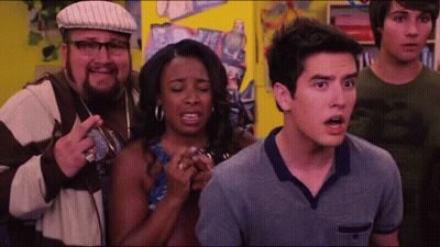Group Standing Before Yellow Wall With Man In Glasses And Hat GIF