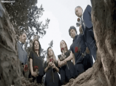Group Standing In Circle Holding Roses In Front Of Tree GIF