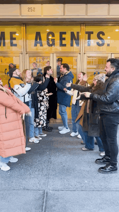 Group Standing In Front Of Agents Building GIF