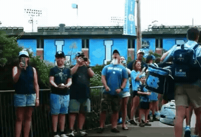 Group Standing In Front Of Blue Building With Letter I GIF