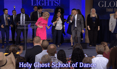 Group Standing In Front Of Lights And Holy Ghost School Of Dance Sign GIF