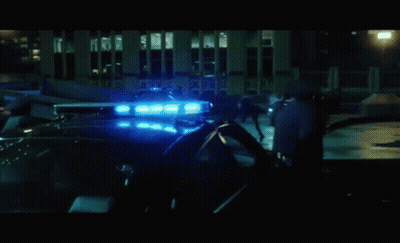 Group Standing In Front Of Police Car In Dark Room GIF