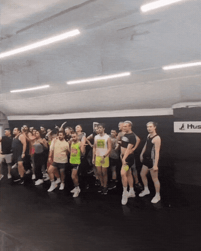 Group Standing In Front Of Wall Saying Hus GIF
