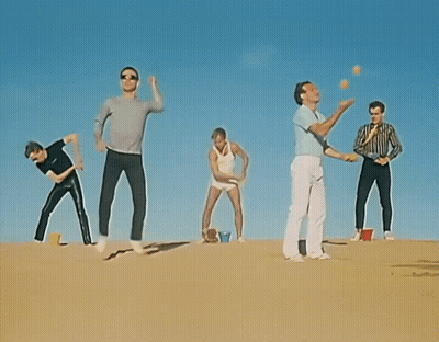 Group Standing On Sand Dune Arms Outstretched GIF