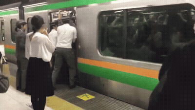 Group Trying To Board Train With Yellow Sign Saying A GIF