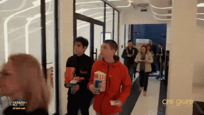Group Walking Down Hallway With Cine Grand Sign GIF