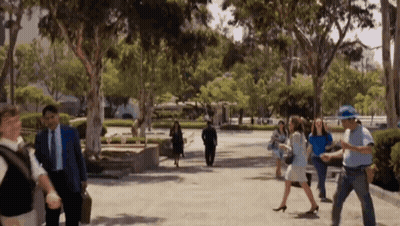 Group Walking Down Sidewalk Surrounded By Trees GIF
