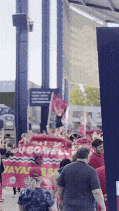 Group Walking Down Street With Ucgowell Sign GIF
