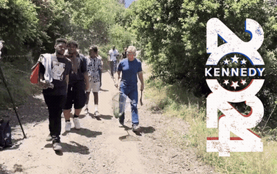 Group Walking Past Kennedy Poster GIF