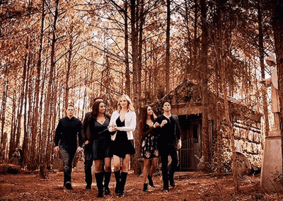 Group Walking Through Forest in Front of House