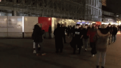 Group Wearing Face Masks Walking Past Kunstwerk Fence GIF