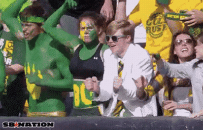 Group With Green And Yellow Paint Cheering In Stadium Saying Senation GIF
