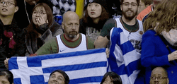 Guys Holding Flags Of Greece In The Audience GIF