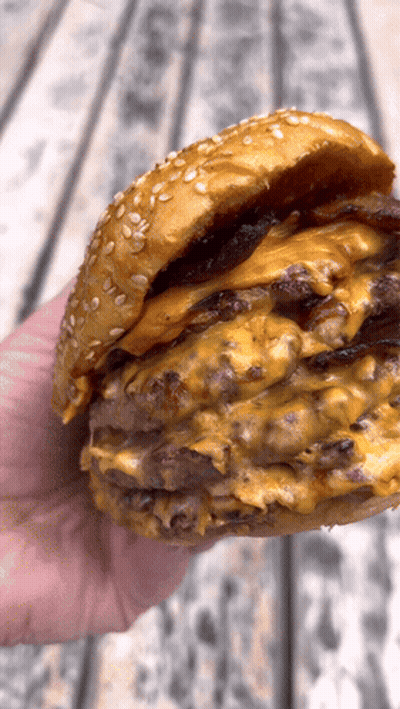 Hand Holding Hamburger With Cheese And Bacon GIF