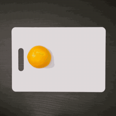Hand Reaching For Orange On Cutting Board GIF