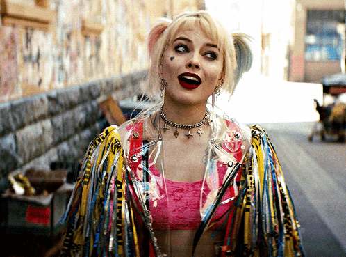 Harley Quinn Is Wearing A Pink Top And A Jacket With Feathers On It GIF