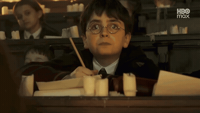 Harry Potter Is Sitting At A Desk In A Classroom With A Candle In His Hand GIF