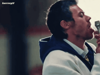Harry Styles In Black Shirt Sitting In Front Of Film Stack GIF
