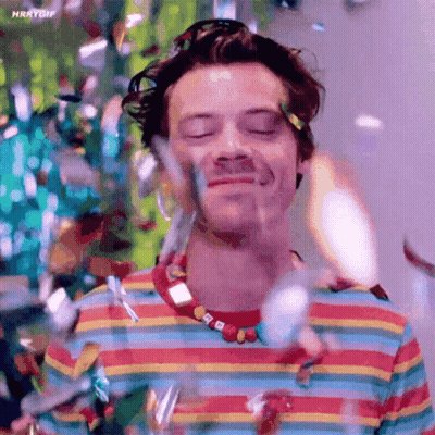 Harry Styles In Colorful Striped Shirt Holding Water GIF