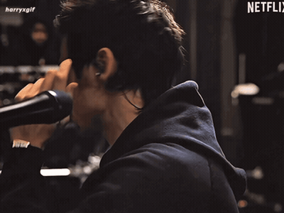 Harry Styles In Green Boa Holding Microphone GIF