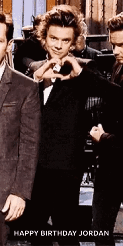 Harry Styles Is Making A Heart Shape With His Hands While Standing Next To A Group Of Men . GIF