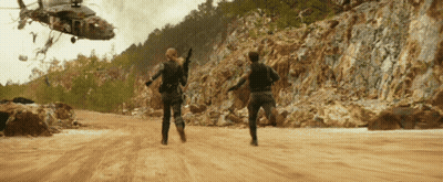 Helicopter Flying Over Dirt Road With Two People Running GIF