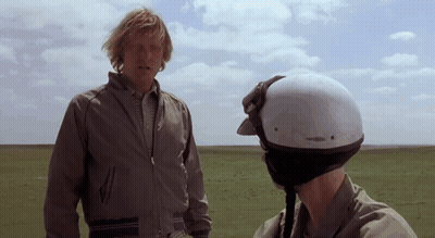 Helmeted Man Talking To Man In Field GIF
