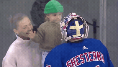 Hockey Goalie Holding Baby In Green Hat GIF