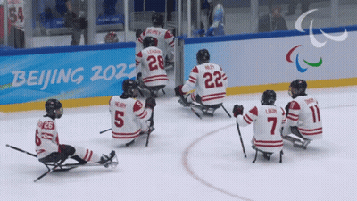 Hockey Players Sitting On Ice In Front Of Beijing 2022 Sign GIF