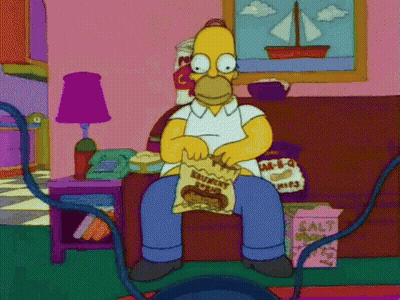 Homer Simpson From The Simpsons Is Sitting On A Couch Eating A Bag Of Chips . GIF