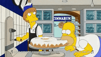 Homer Simpson Is Eating A Cinnamon Roll In A Bakery GIF