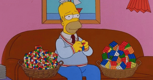 Homer Simpson Is Playing With A Rubik 'S Cube On A Couch GIF